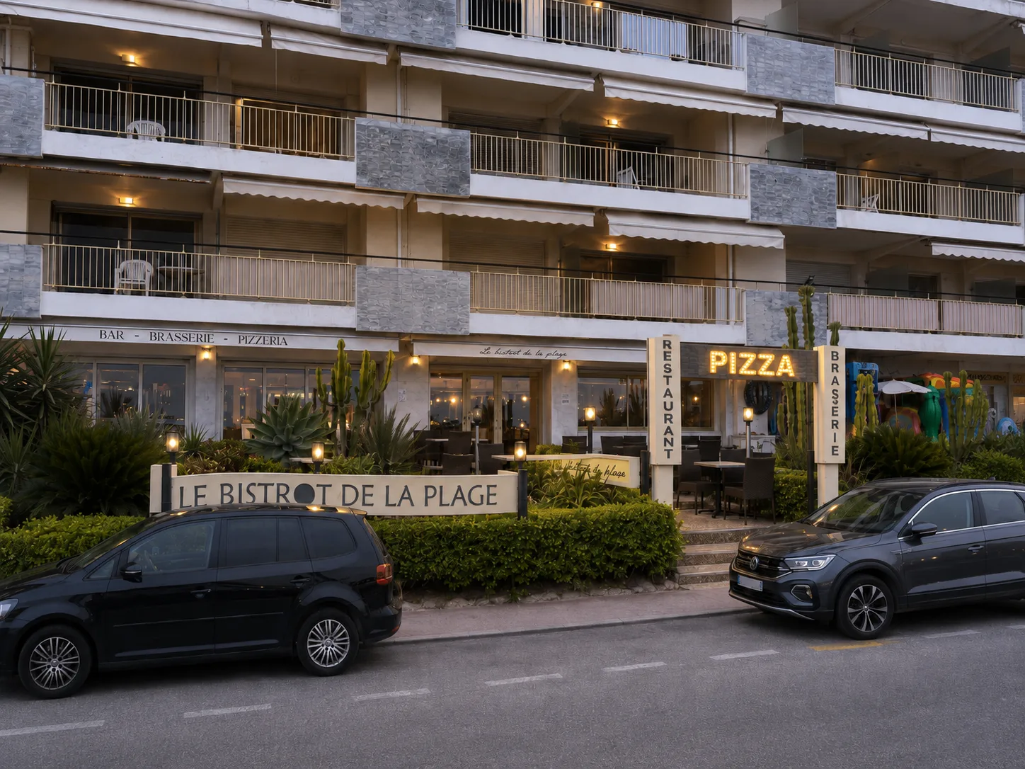 La façade du Bistrot de la Plage au crépuscule, terrasse éclairée et enseigne Pizza